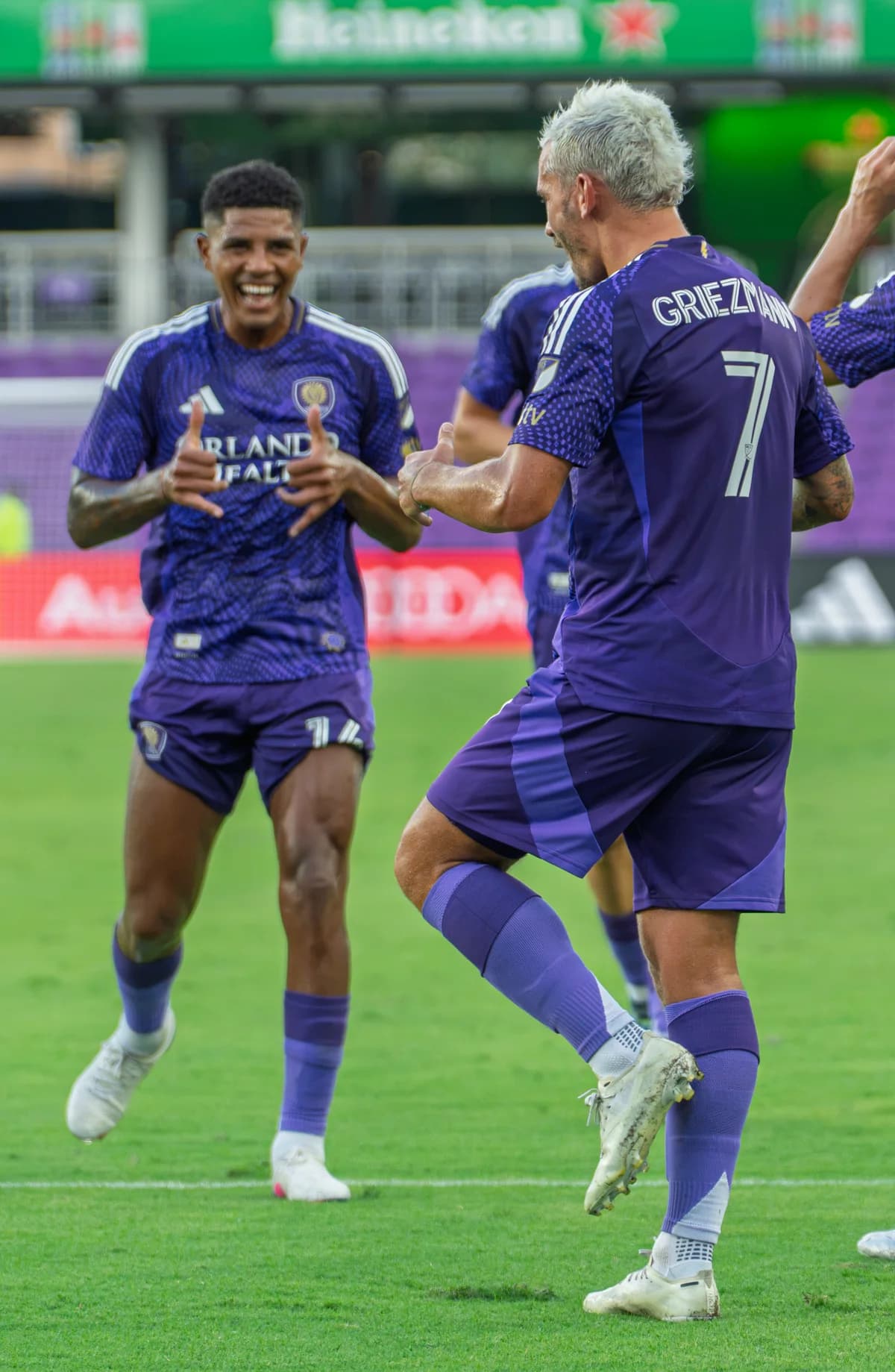 Two purple-shirted teammates celebrating together on the field